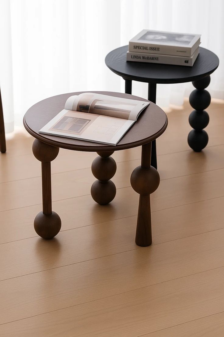 Luxury Two round wooden side tables with ball-shaped legs on a light wood floor.