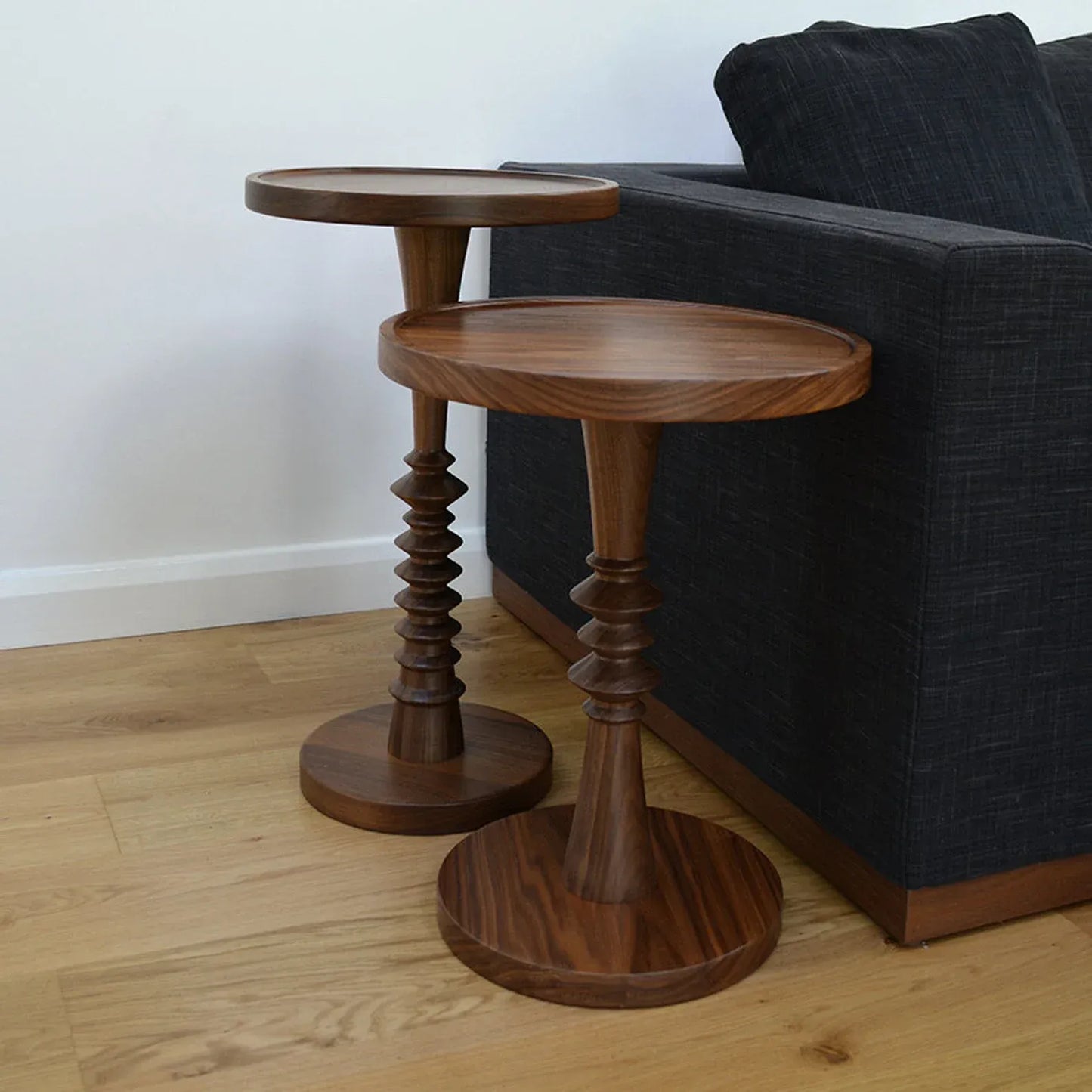Rustic Two wooden side tables with a dark sofa in the background.