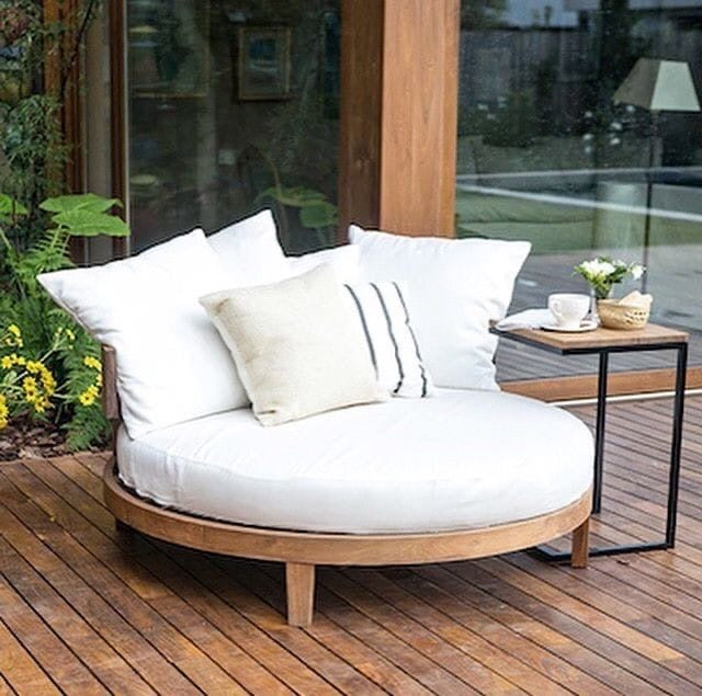 Round outdoor sofa with white cushions on a wooden deck