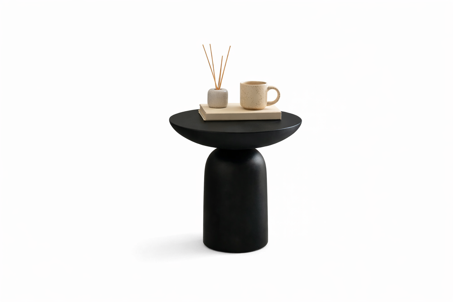 minimalist Black side table with a cup, book, and decorative items on a white background