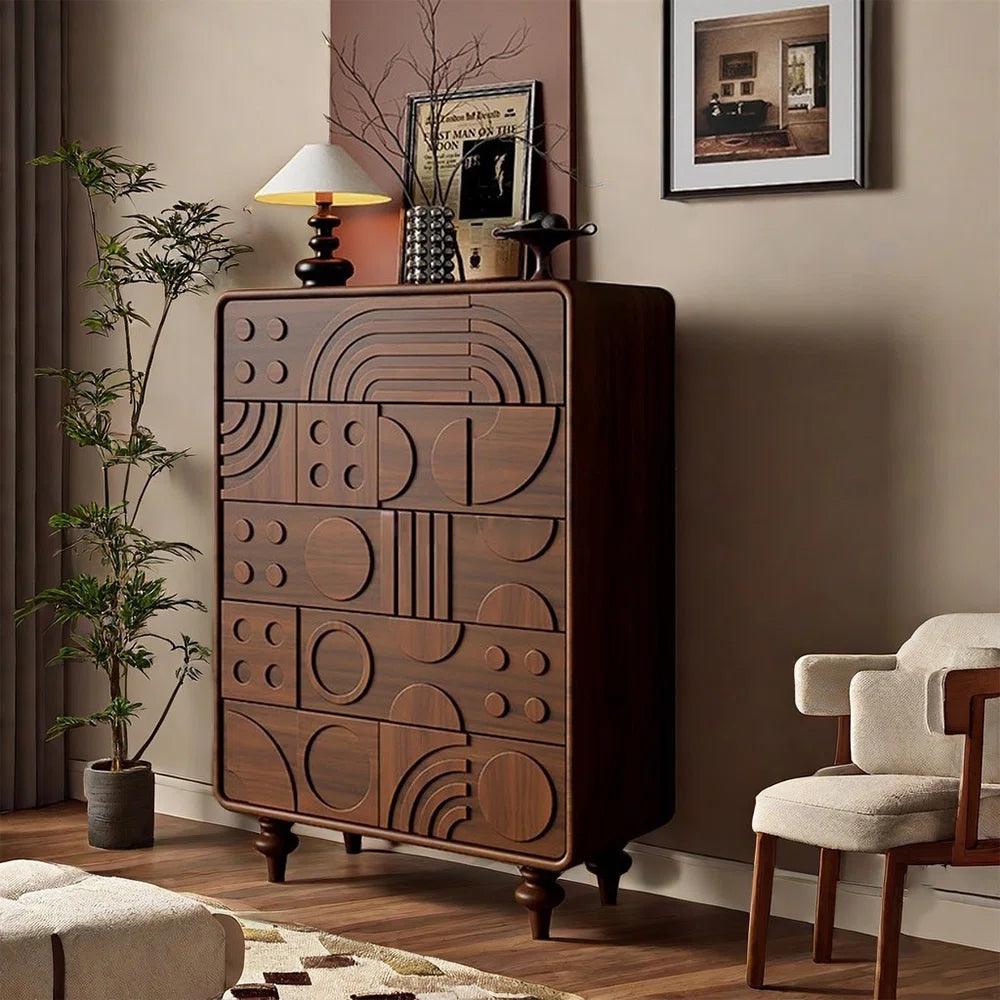 Wooden dresser with geometric patterns in a room with a chair, plant, and framed picture.