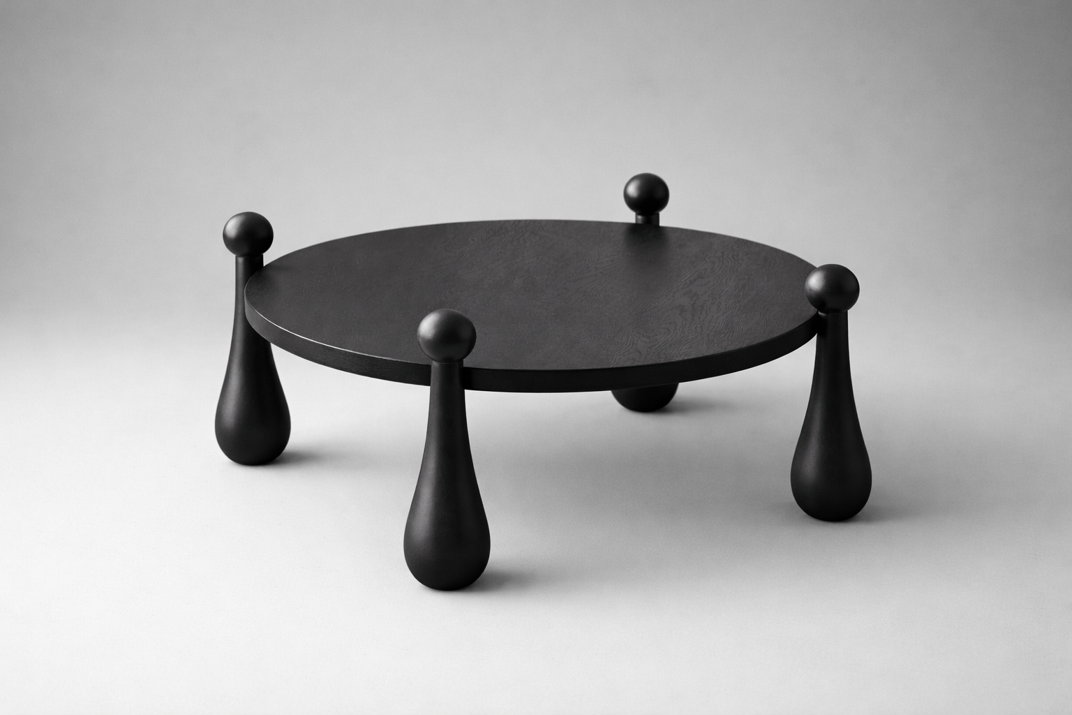 Black round table with unique legs on a gray background