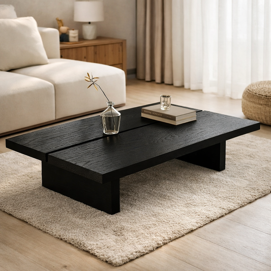 Black coffee table in a living room with a vase and book on top