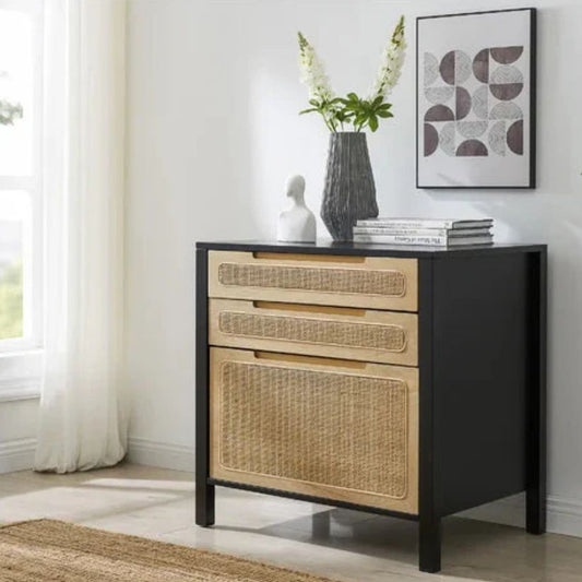 A black lateral file cabinet with birch wood and rattan details, placed in a room with decorative items on top.